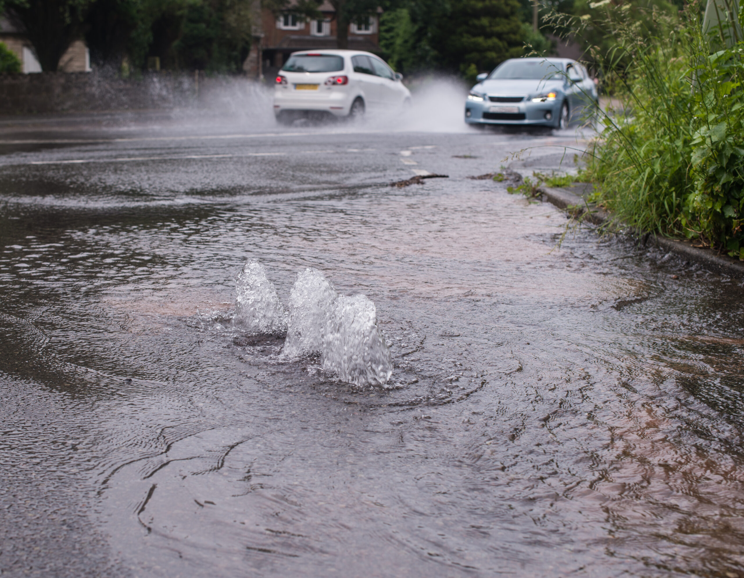 Cars driving through floodwater from a burst water main.