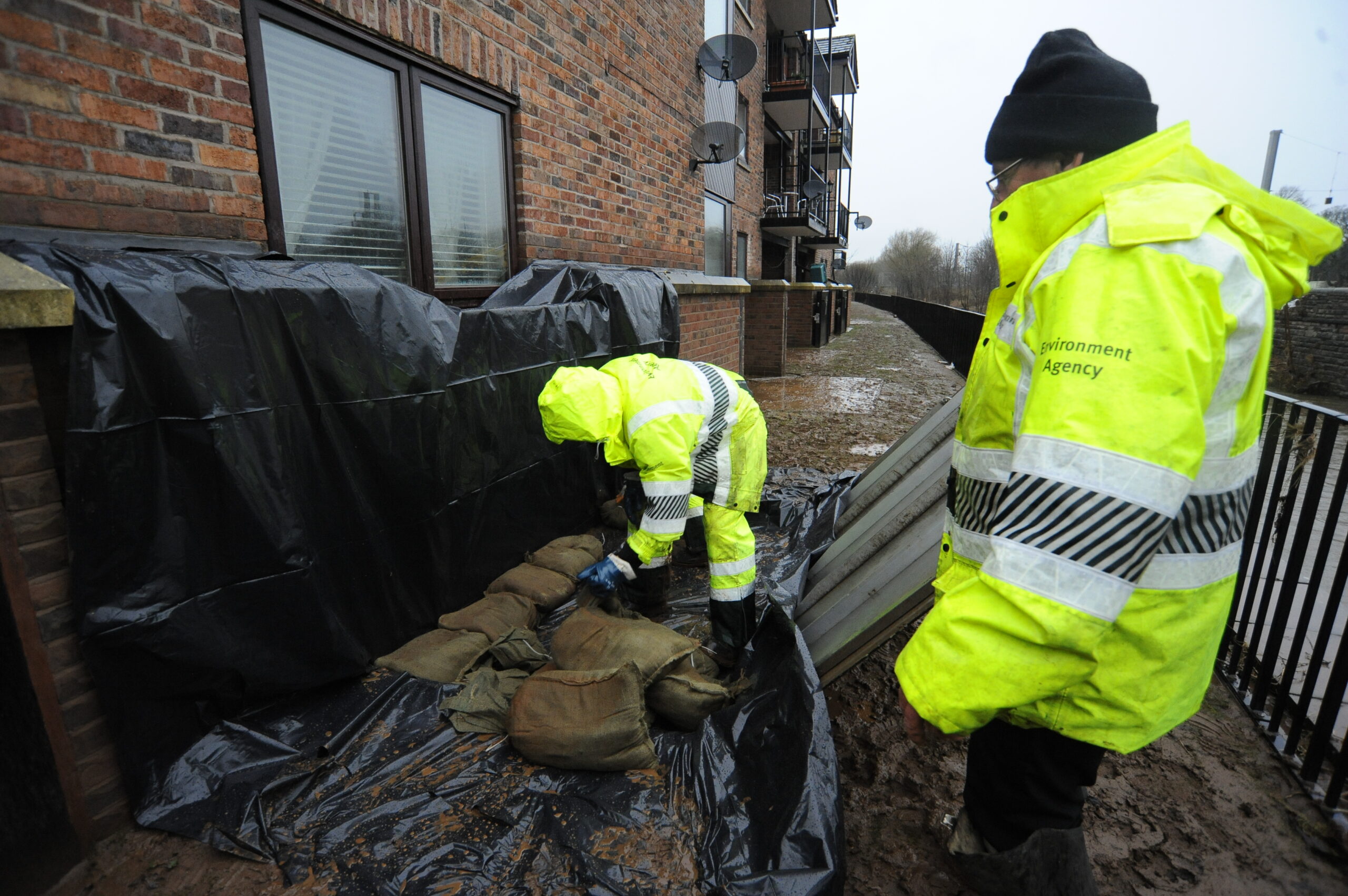 Environment Agency staff repairing wall to prevent house from flood water, Caldew Maltings.