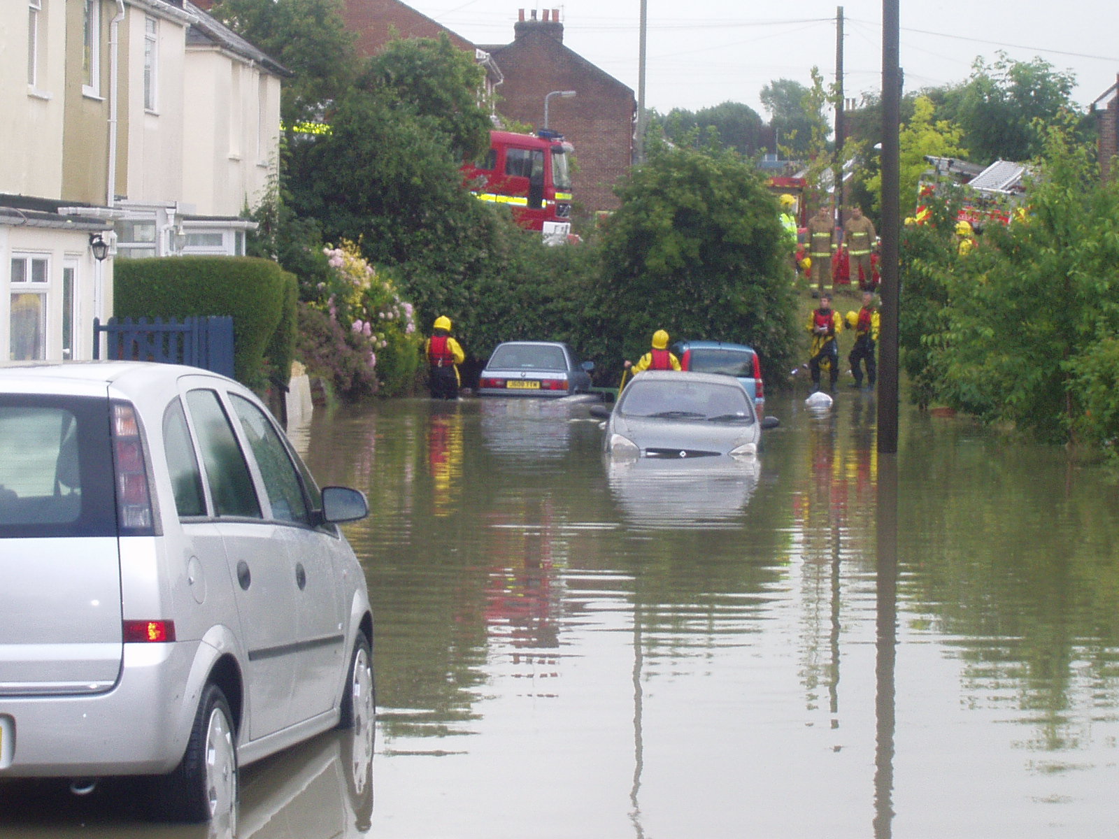 Flooded street with submerged cars, with Fire and rescue engine and workers.