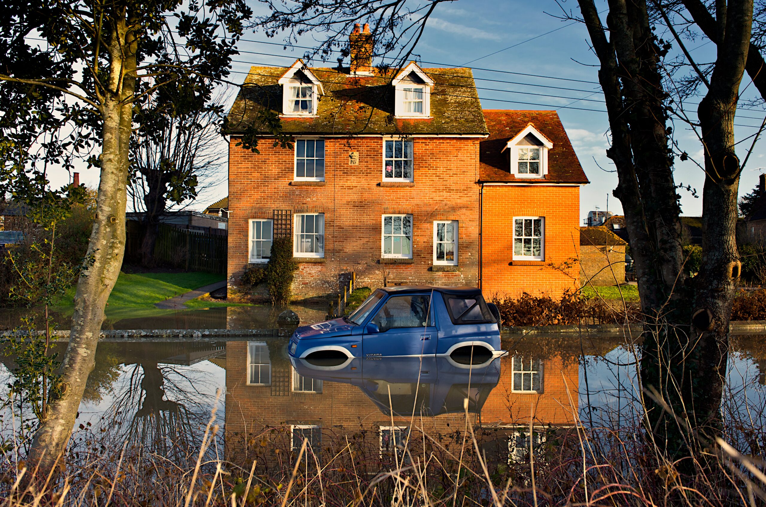 House with car on flooded street.