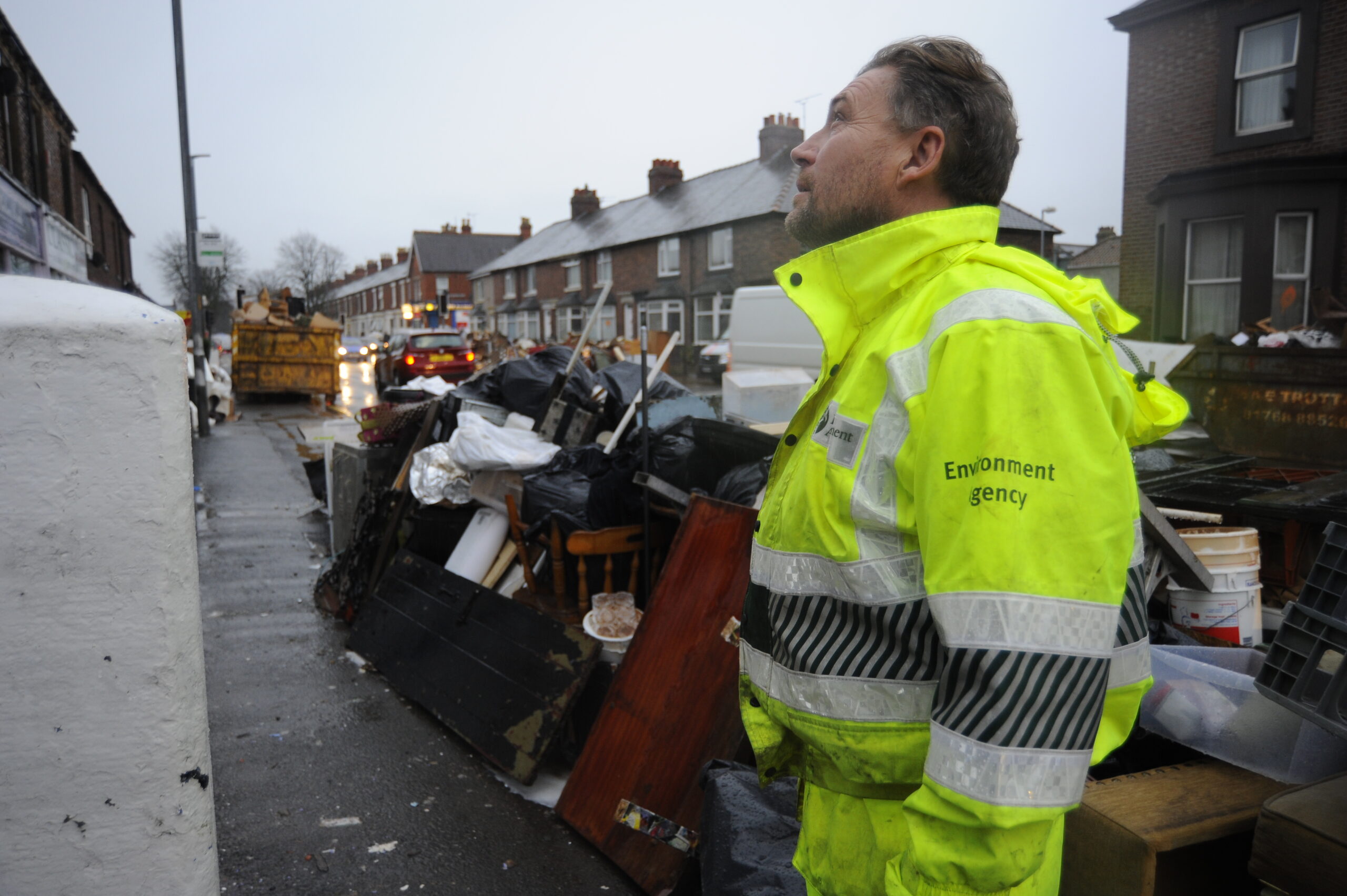 Environment Agency staff member helping with clean-up after a flood on a residential street.