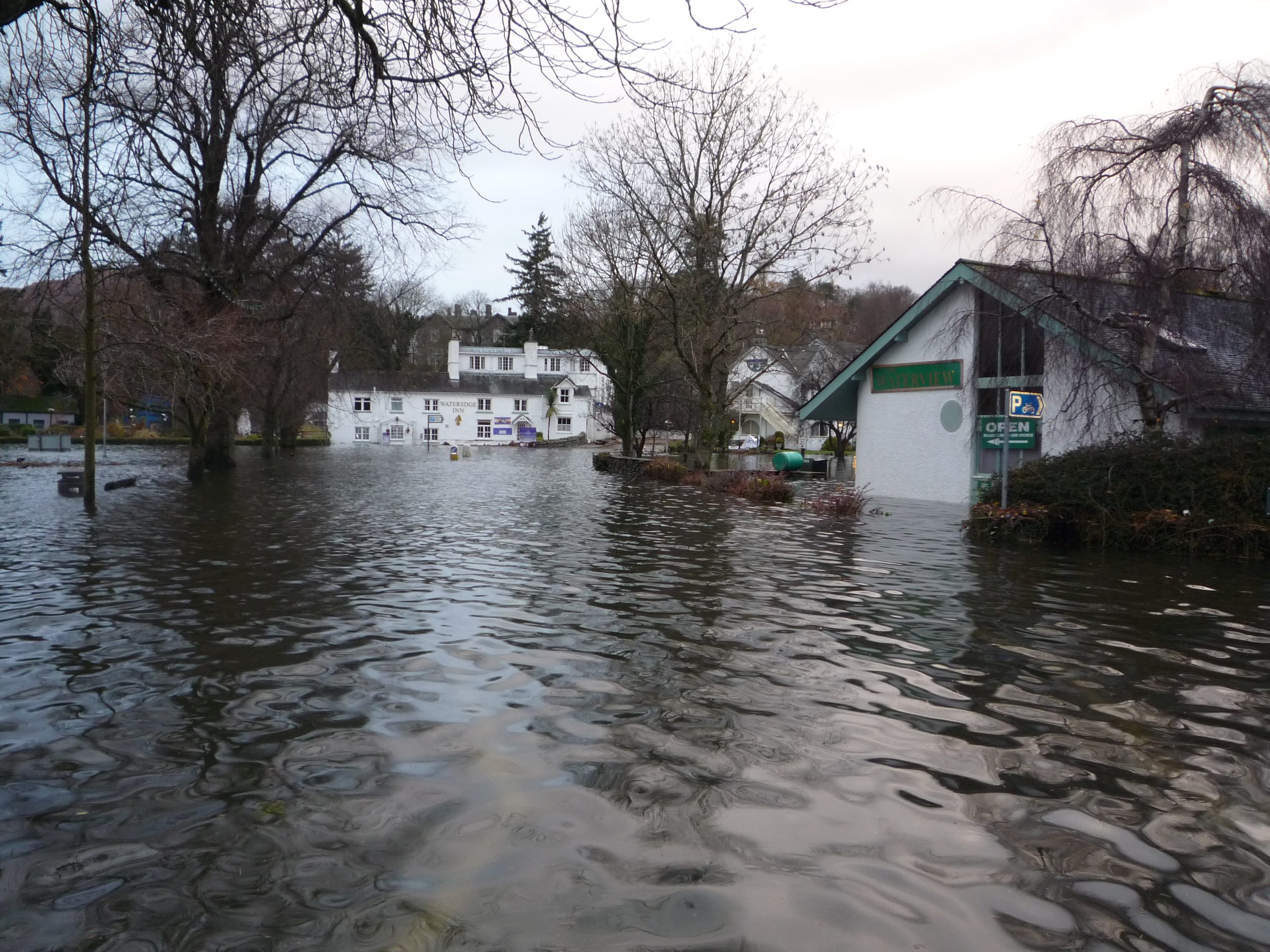 A village shop and houses surrounded by floodwater.
